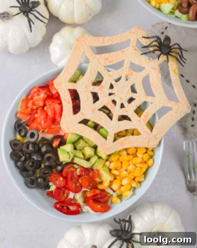 Spooky Taco Bowls 1 halloween taco salad with spider tortilla in a white bowl in plastic spiders crawling around the table