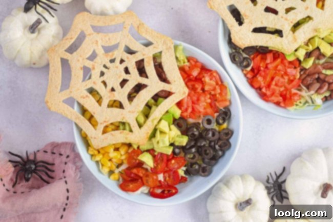 Spooky Taco Bowls 2 halloween taco salad with spider tortilla in a white bowl and pumpkin in background