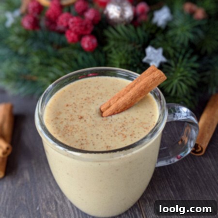 Healthy Eggnog Classic and Plant-Based 3 photo of a cup of creamy eggnog with a cinnamon stick and holiday decorations in the background