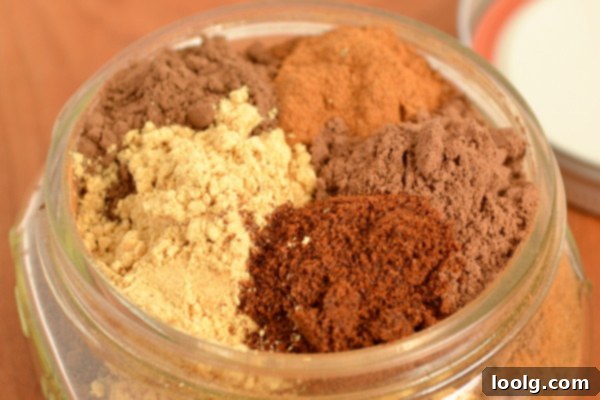 Homemade Pumpkin Pie Spice Blend A jar of homemade pumpkin pie spice blend with whole spices like cinnamon sticks and star anise beside it.