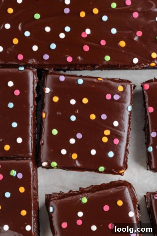 Fudgy brownie slice topped with chocolate ganache and sprinkles