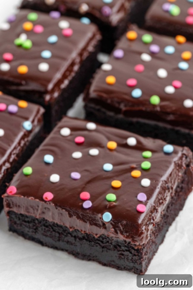 Close-up of a fudgy brownie with ganache and colorful sprinkles on top