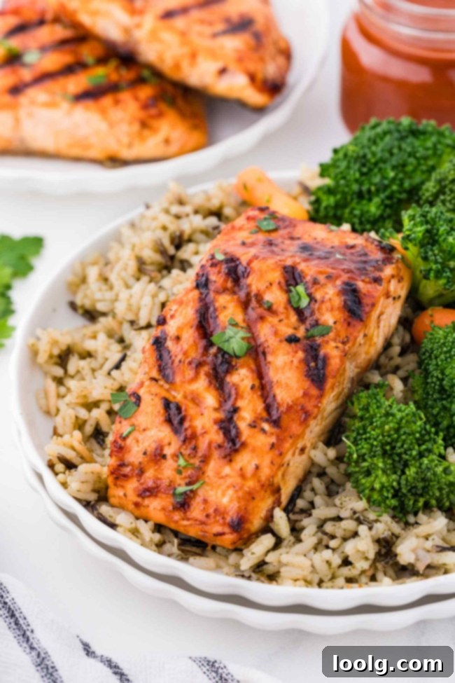 Grilled Salmon Perfection 2 Deliciously barbequed salmon fillet served on a white plate with wild rice and steamed broccoli, showcasing a perfect grilled dinner.