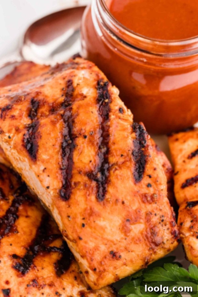 Grilled Salmon Perfection 7 Perfectly grilled barbequed salmon served on a white plate, with a side of BBQ sauce for dipping.