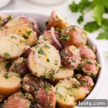 no mayo potato salad in a white bowl with fresh parsley in background