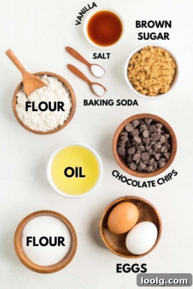 Ingredients for making chocolate chip cookies without butter are neatly laid out on a surface, including oil, sugars, flour, eggs, and chocolate chips.