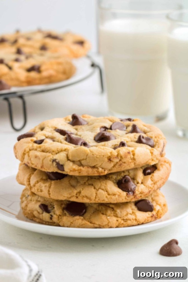 A photo of a stack of three perfectly baked chocolate chip cookies made with oil instead of butter, showing their soft texture and melted chocolate.