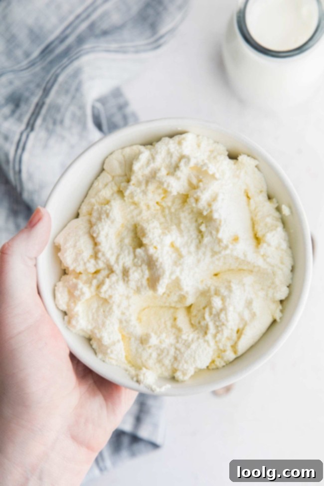 Hand holding a bowl of freshly made ricotta cheese, showing its texture