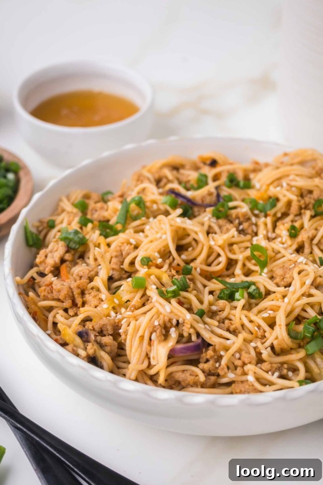 Sticky Honey Garlic Noodles with Sesame and Scallions 2 closeup of honey garlic noodles in a white bowl on a white table