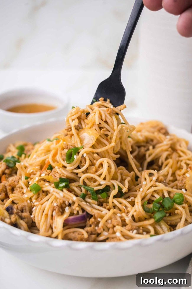 Sticky Honey Garlic Noodles with Sesame and Scallions 6 fork picking up some noodles from a bowl of honey garlic noodles