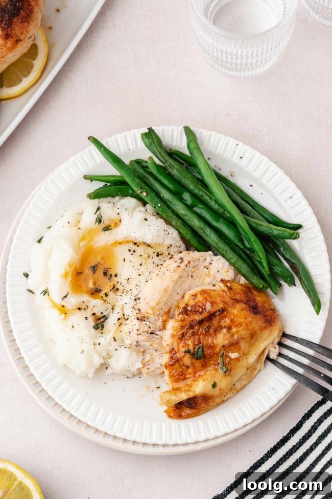 sliced chicken on a white plate with mashed potatoes and green beans