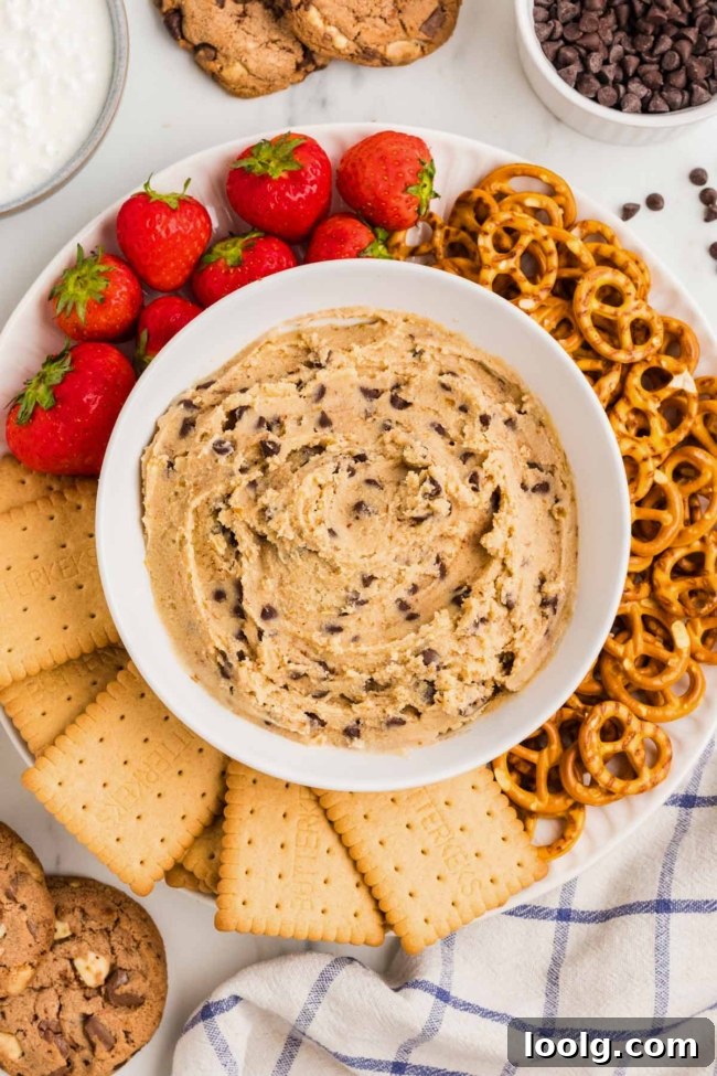 white plate with cookies, strawberries and pretzels and a white bowl of cottage cheese cookie dough