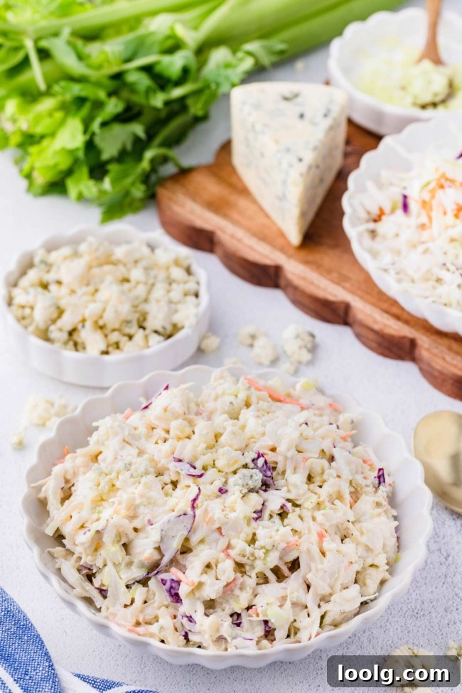 Creamy Blue Cheese Coleslaw with Tangy Dressing 2 blue cheese slaw in a white bowl with more blue cheese in the background together with the other ingredients