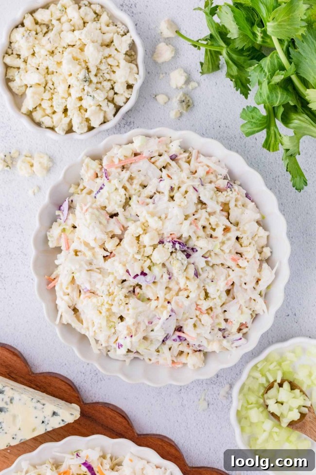 Creamy Blue Cheese Coleslaw with Tangy Dressing 7 blue cheese coleslaw in a white plate on a white table with celery, parsley and blue cheese in the background