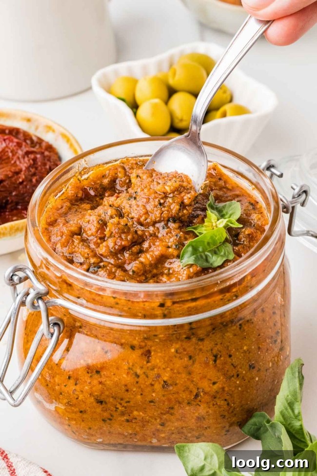 spoon digging into a jar of red pesto