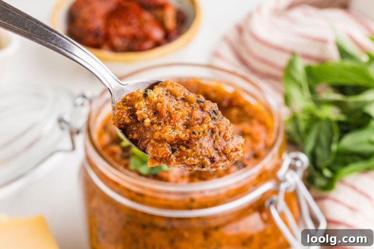 spoon digging into sun-dried tomato pesto in a mason jar
