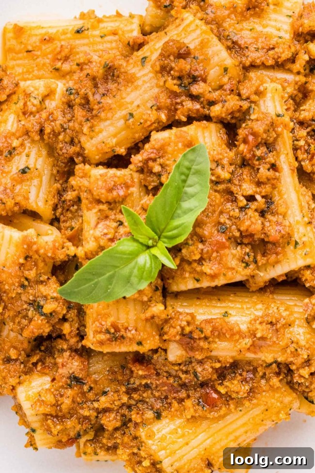 close-up of sun-dried tomato pesto pasta on a white plate with basil on top