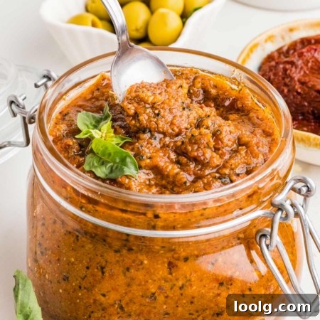 spoon digging into a jar of sun-dried tomato pesto