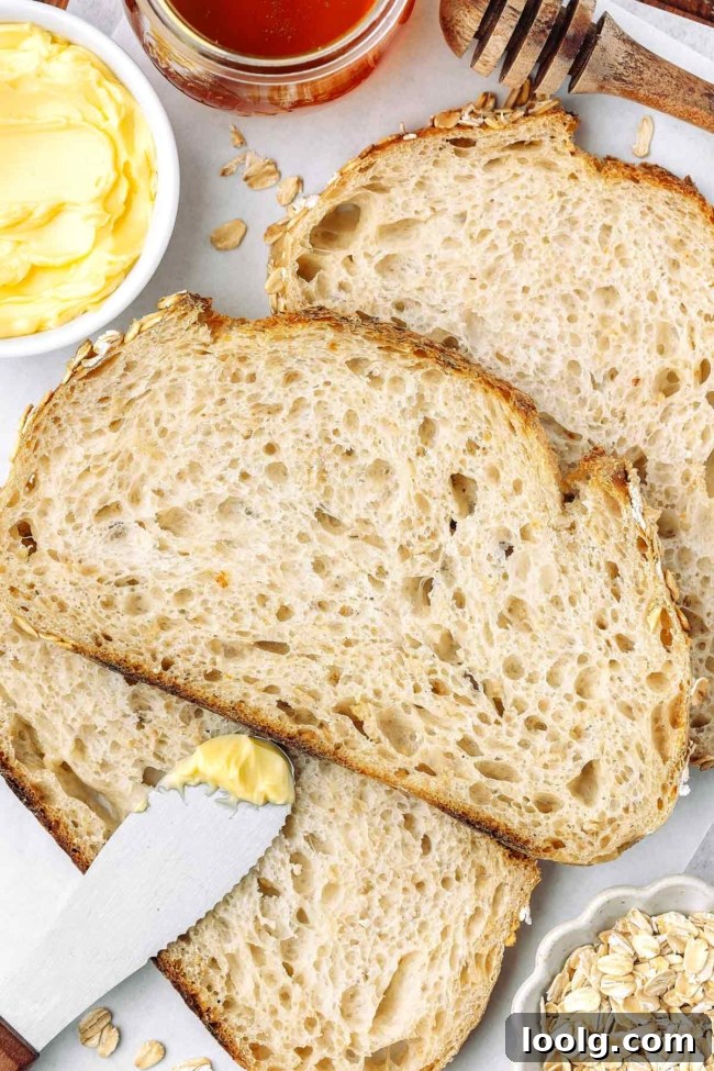 close-up overhead shot of a slice of oatmeal sourdough on white parchment paper with butter in background
