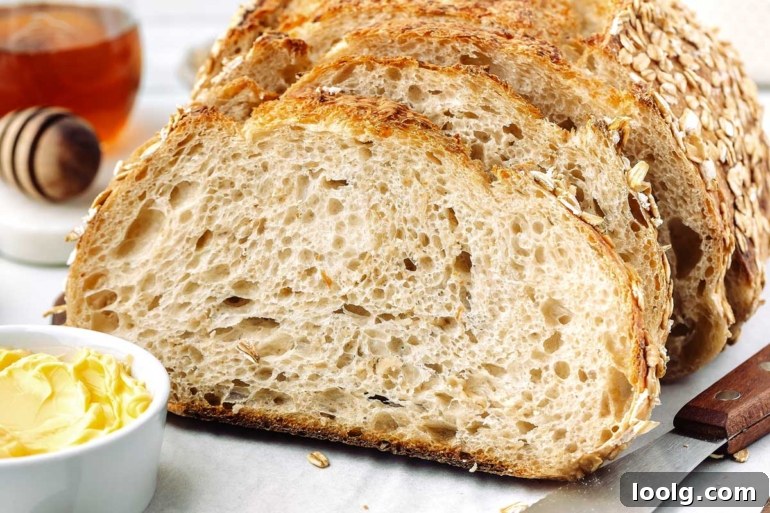 horizontal shot of oatmeal sourdough bread on a cutting board with honey in background