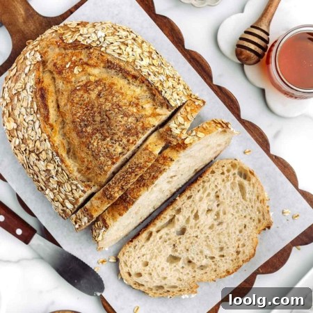 overhead shot of sliced up honey oatmeal sourdough bread on a cutting board with honey in background