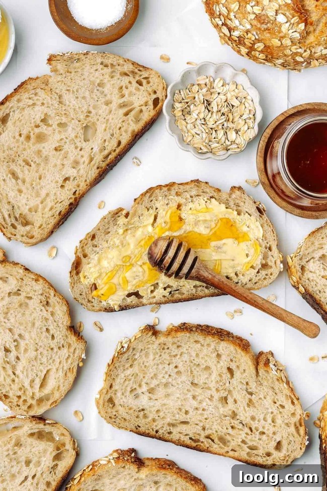 honey being drizzled over a buttered piece of honey oatmeal sourdough bread