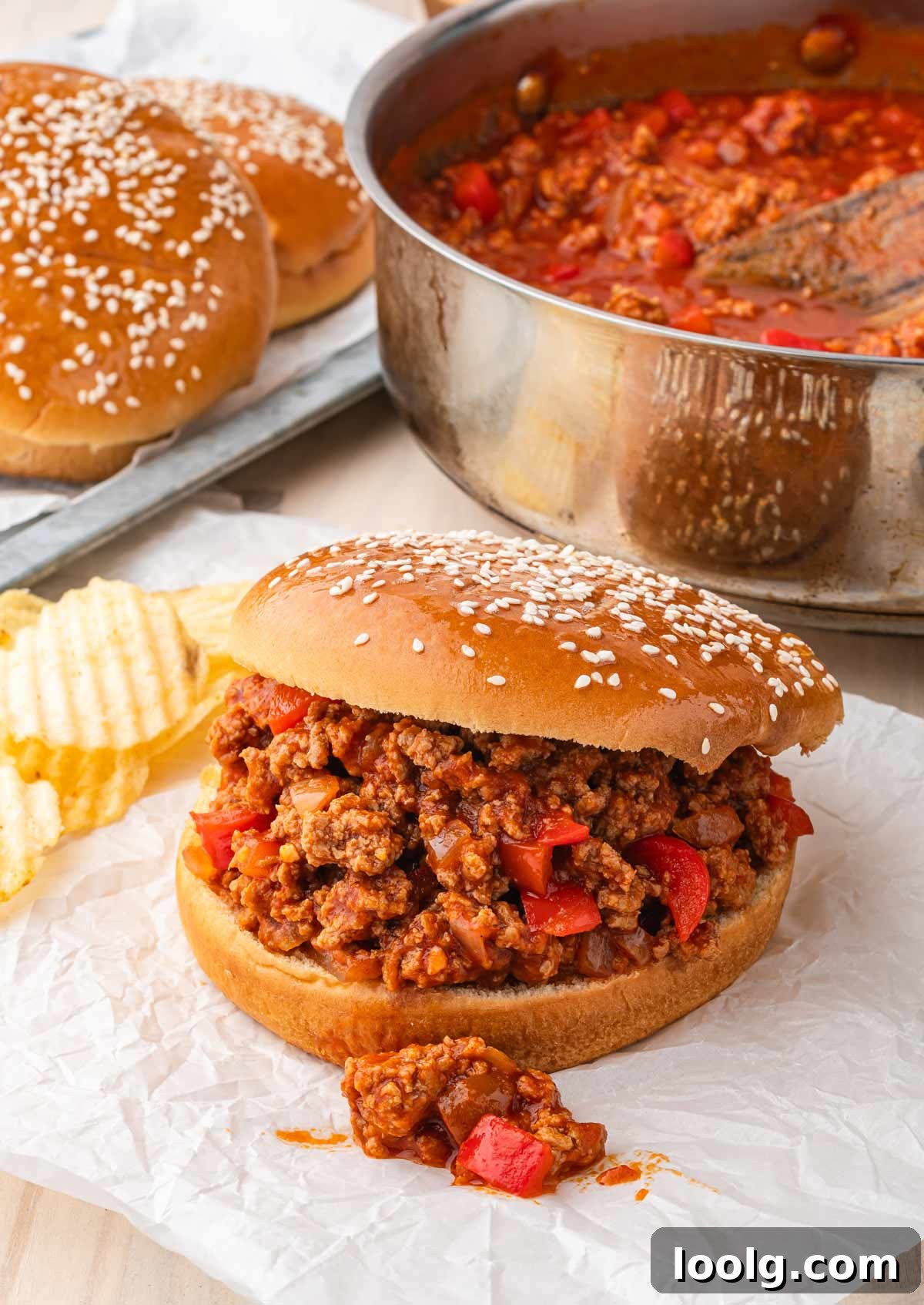 two ground turkey sloppy joes on parchment paper with the skillet in the background