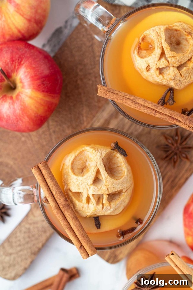 Shrunken Head Apple Cider: Spooky Halloween Drink Recipe 5 Warm spiced apple cider topped with a carved shrunken apple head and garnished with cinnamon sticks and cloves.