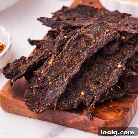 Homemade Smoky Venison Jerky Recipe 14 Savory venison jerky strips seasoned with spices, displayed on a wooden cutting board.